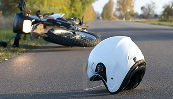 Motorcycle and a helmet on the side of a road, representing motorcycle accidents